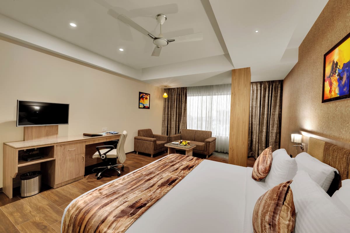 A hotel room with a bed, desk, chair, television, and a ceiling fan.