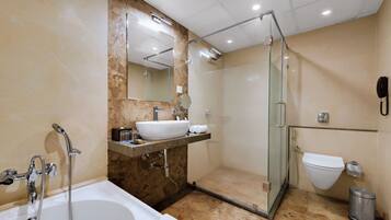 A modern bathroom with a bathtub, a glass-enclosed shower, a sink with a marble countertop, and a toilet.