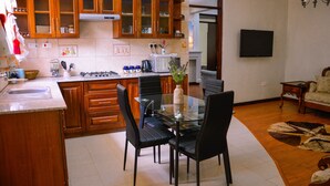 Une cuisine moderne avec des meubles en bois, une table à manger en verre et des chaises noires.