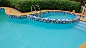 Une piscine bordée de mosaïques et dotée d’un escalier en métal.