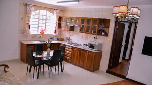 Une cuisine avec des meubles de rangement en bois, une table à manger avec des chaises, une cuisinière à gaz et un four à micro-ondes.