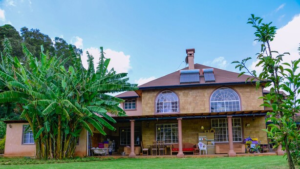 Une maison à deux étages avec une grande véranda à l’avant, une cheminée et un garage.