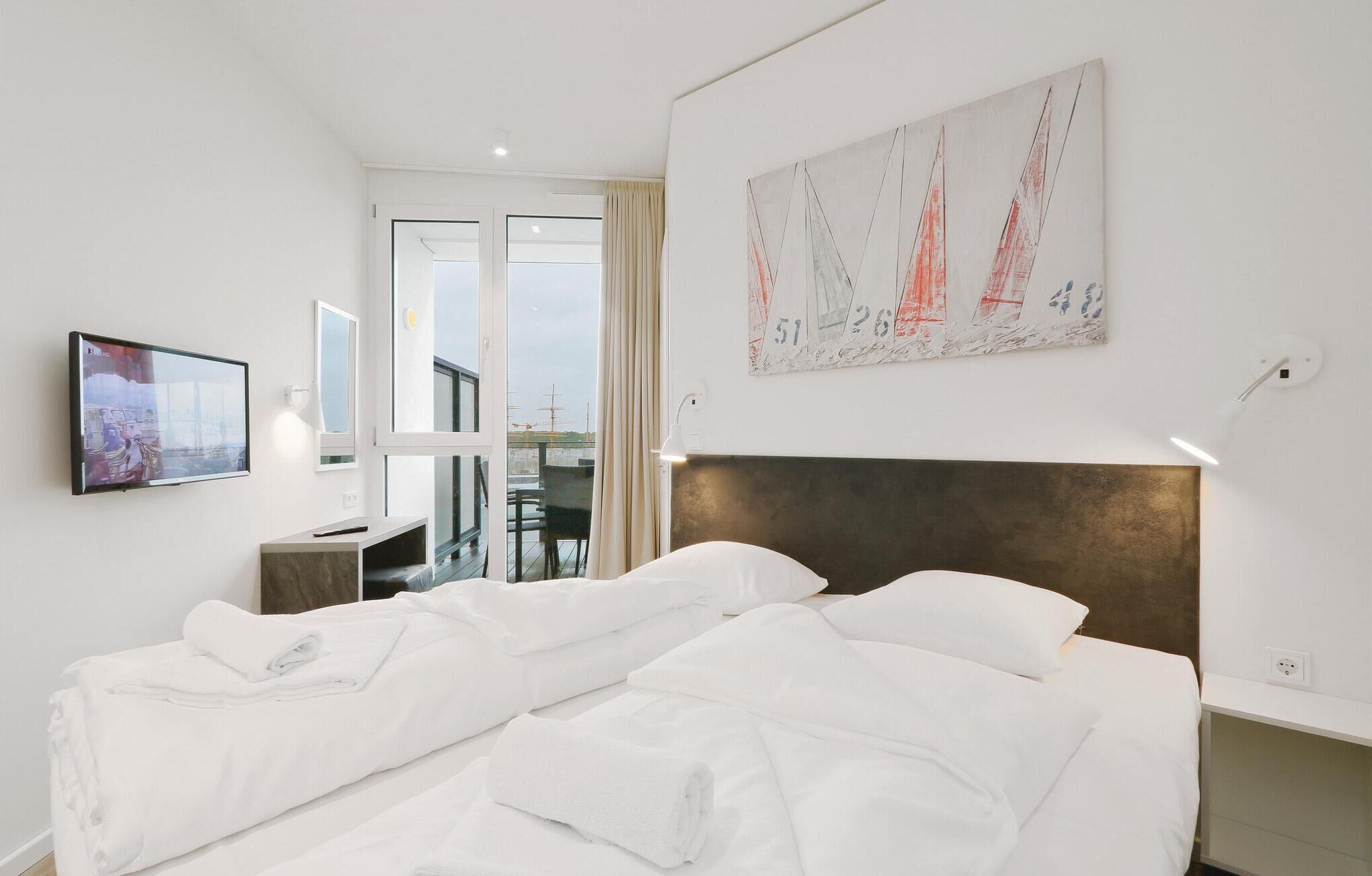 A hotel room with a large bed, a desk with a chair, a television, and a window with curtains.