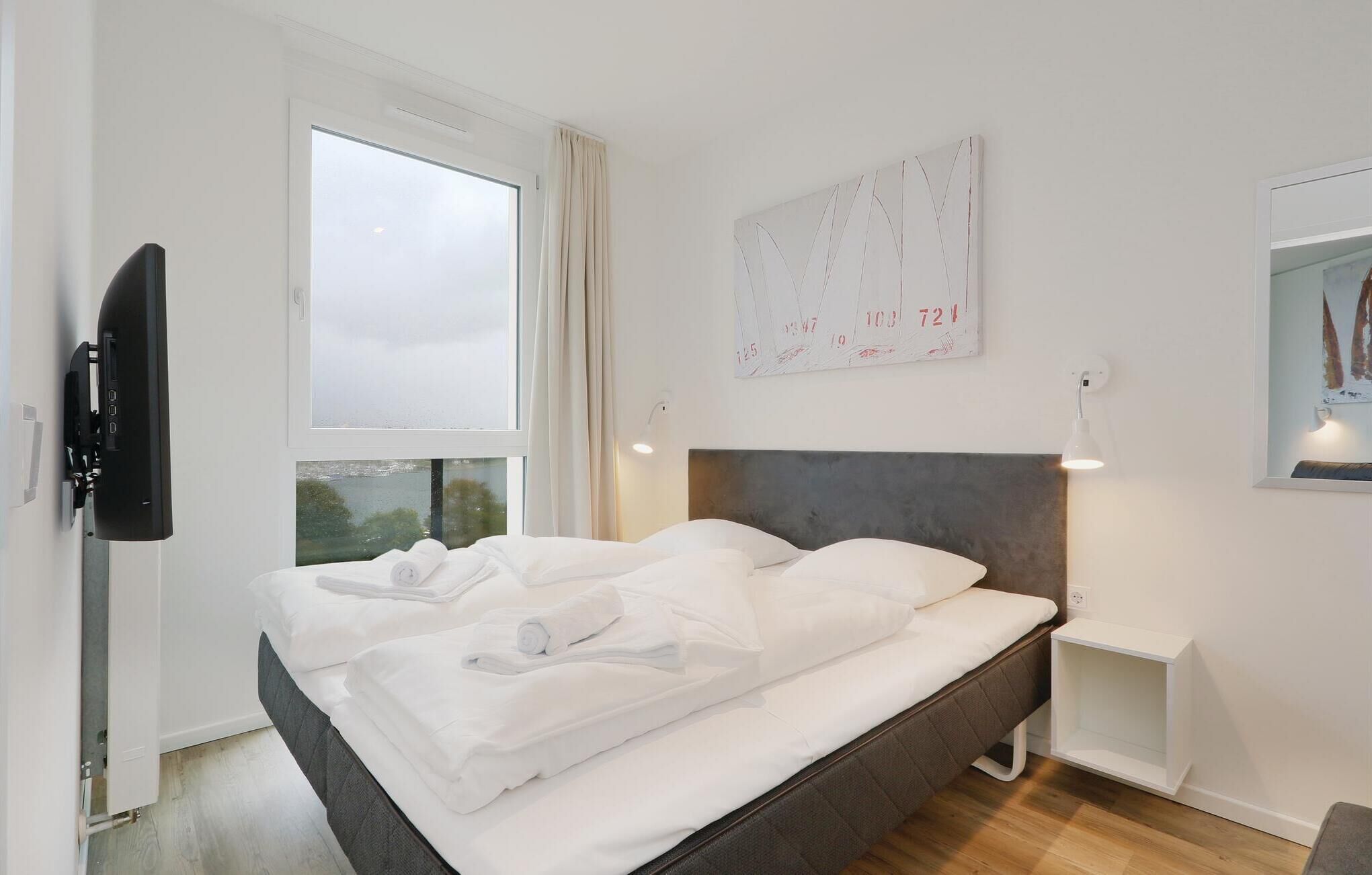 Ein Hotelzimmer mit einem Bett, einem Fernseher, einem Nachttisch und einem Fenster mit Vorhängen.