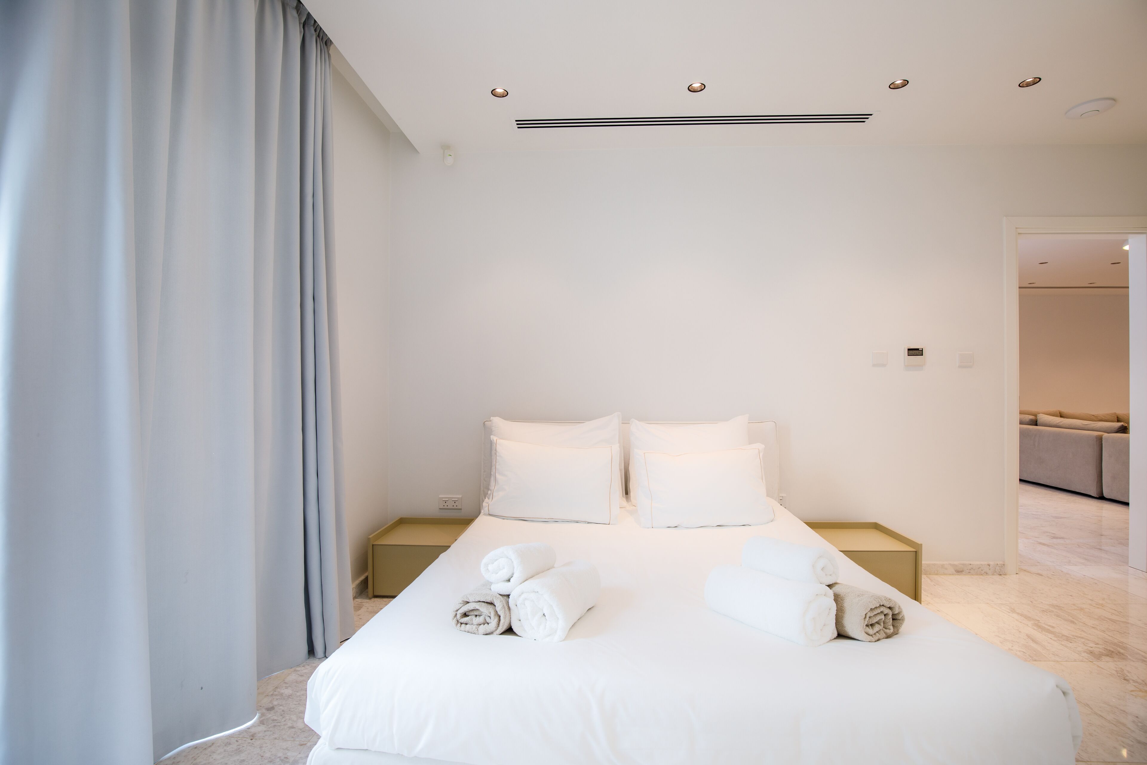 Une chambre d’hôtel moderne avec un grand lit, deux tables de chevet et une vue sur l’espace de vie.