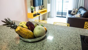 A kitchen counter with a fruit bowl containing pineapple, banana, and melon. - Landscape Diamond (Fortaleza)
