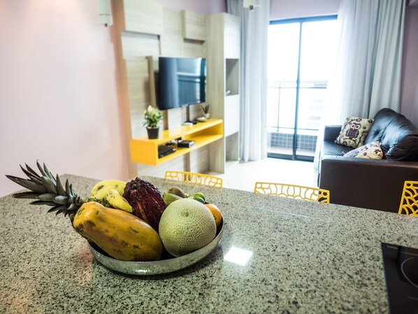 A kitchen counter with a fruit bowl containing pineapple, banana, and melon. - Landscape Diamond (Fortaleza)