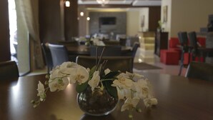Een eetgedeelte met een tafel waarop een vaas met witte bloemen staat.