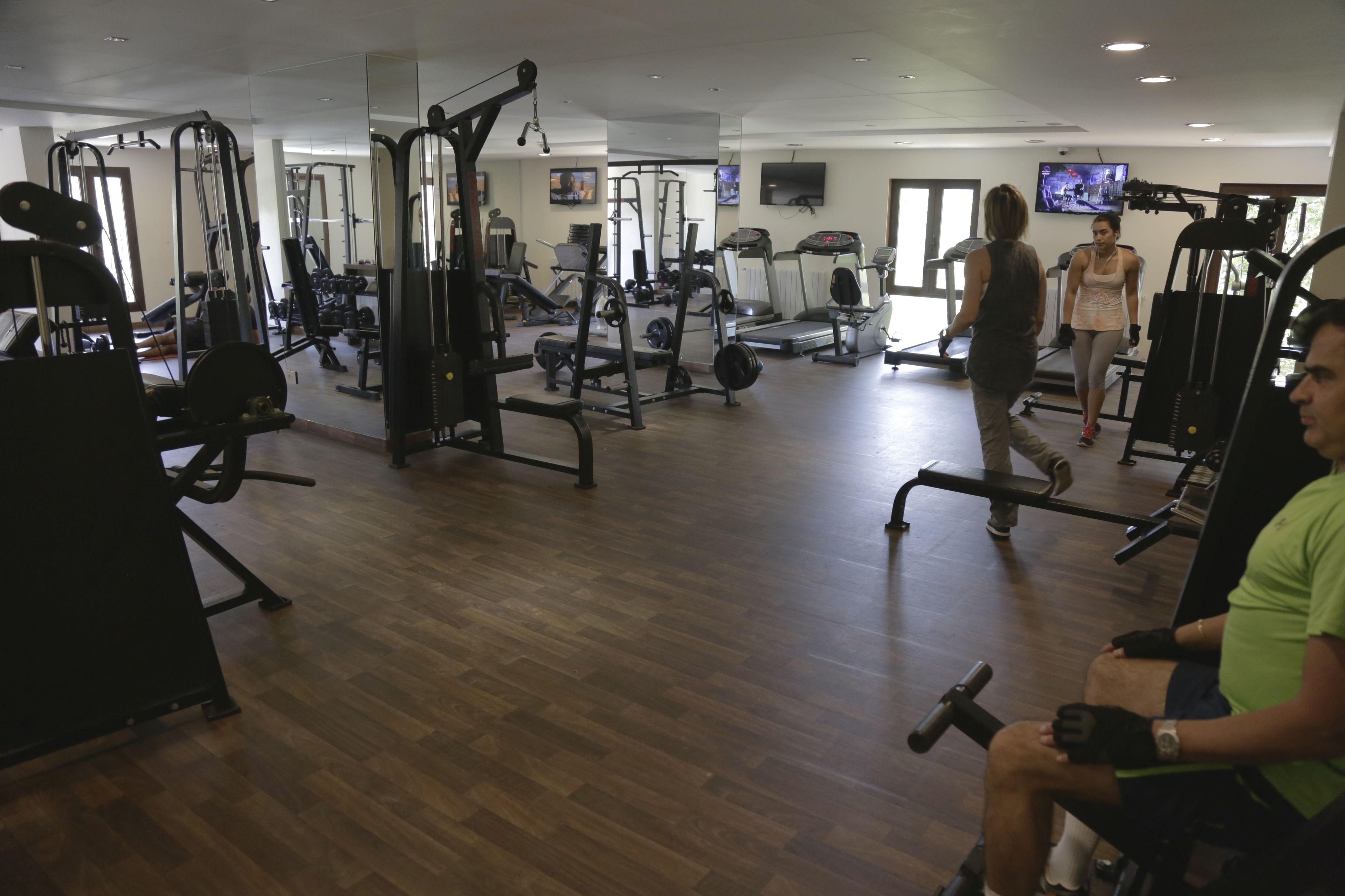 A gym with various exercise equipment, a television, and a mirror.