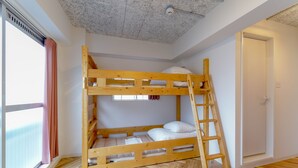 Une chambre avec un lit superposé, une échelle en bois, une fenêtre avec des rideaux et un parquet en bois à motifs en chevrons.