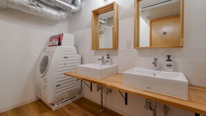 Une salle de bain moderne avec deux lavabos, un miroir et un lave-linge encastré.