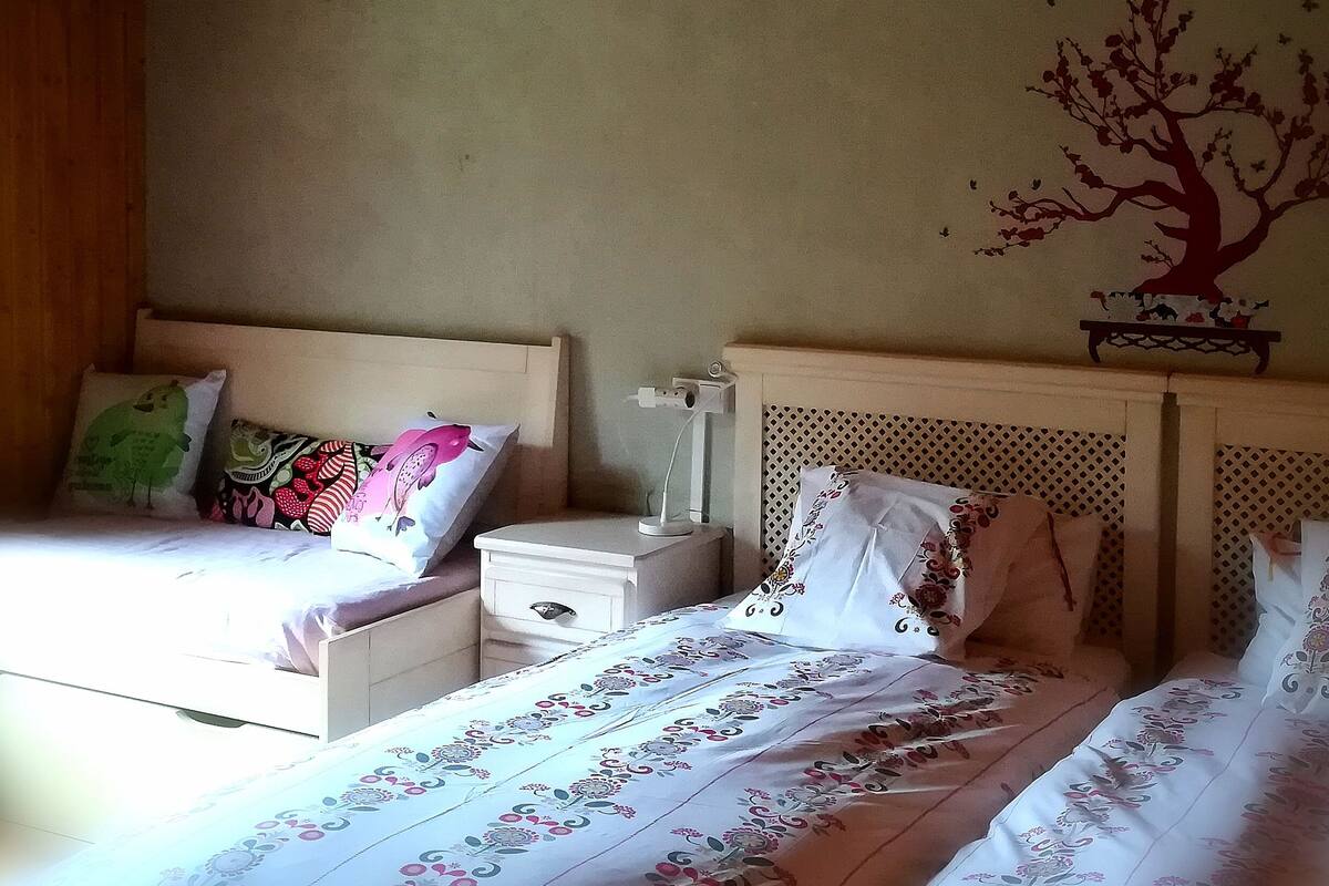 Een slaapkamer met twee bedden, een nachtkastje en een wandlamp.