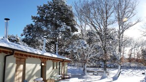 A snow-covered outdoor area with a building, benches, and trees.