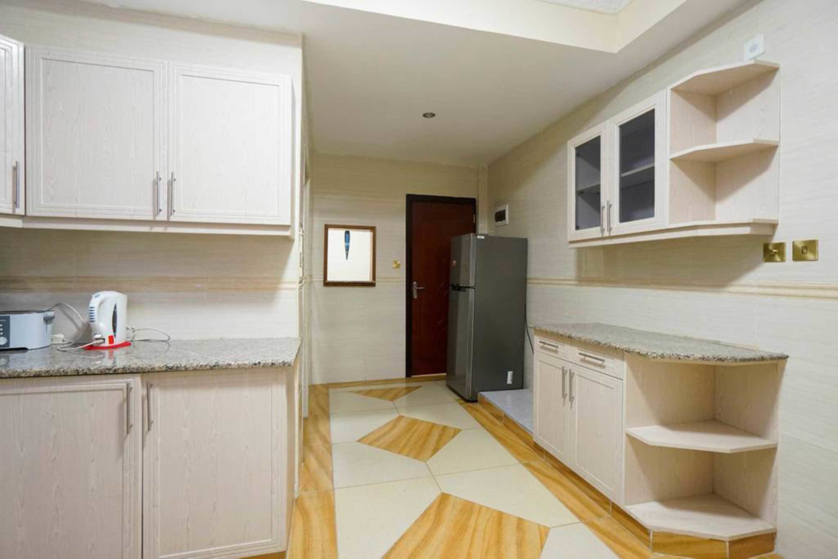 Eine Küche mit weißen Schränken, einem Kühlschrank und einer Mikrowelle auf der Arbeitsfläche.