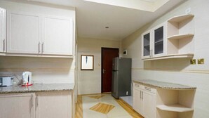 A kitchen with white cabinets, a refrigerator, and a microwave on the counter.