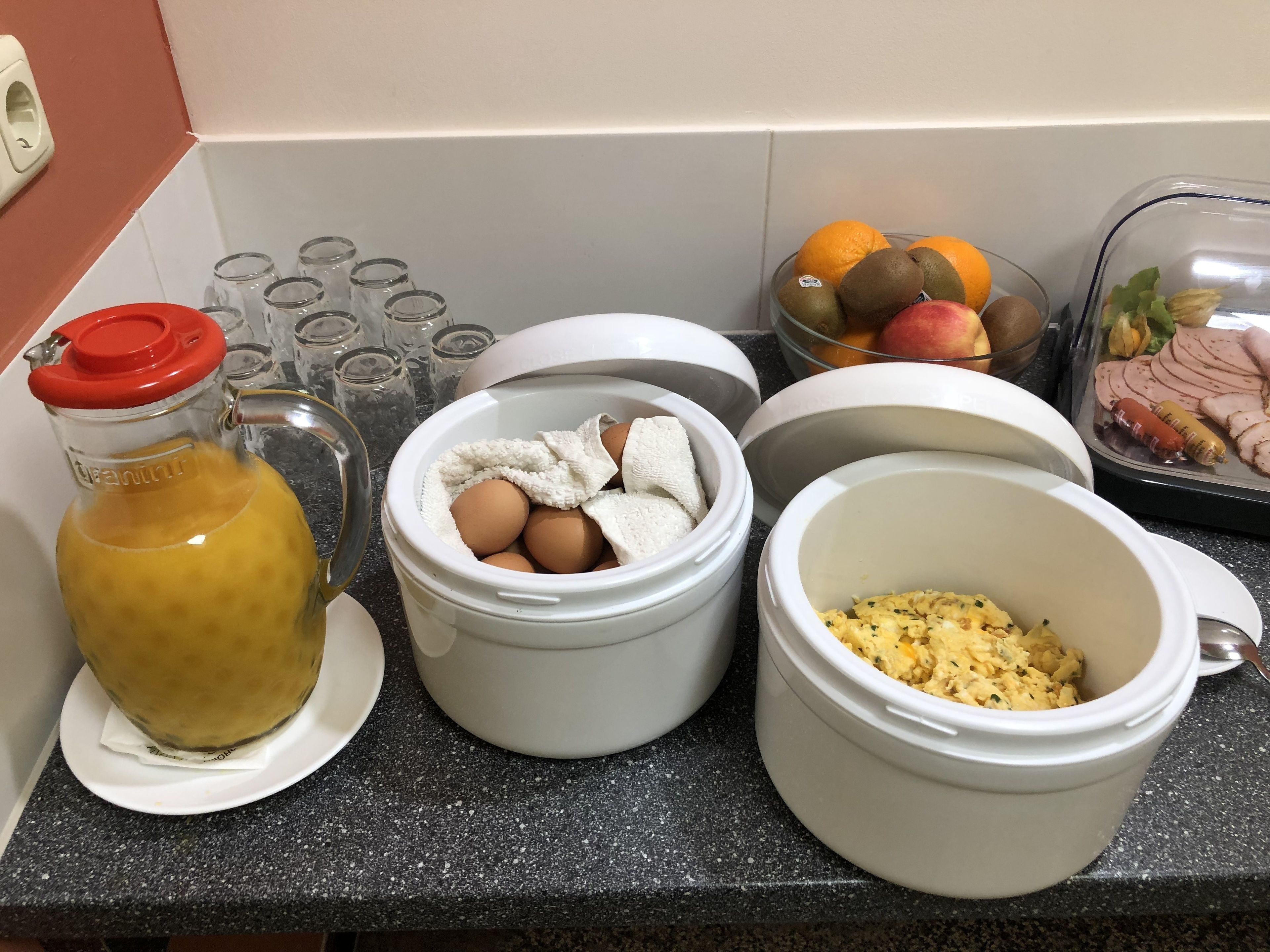A kitchen counter with various food items and containers, including a bottle of liquid, eggs, and a dish with scrambled eggs.