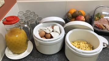 A kitchen counter with various food items and containers, including a bottle of liquid, eggs, and a dish with scrambled eggs.