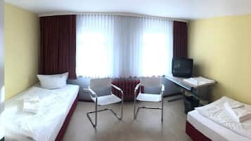 A hotel room with two beds, a desk with a computer, a chair, and a television.