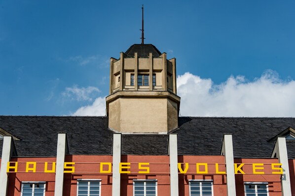 Ein Gebäude mit einem Turm und der Aufschrift 'HAUS DES VOLKES' an der Fassade.