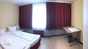 Ein Hotelzimmer mit zwei Betten, einem Schreibtisch und einem Stuhl.