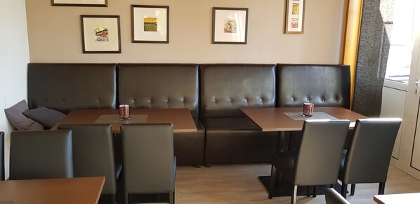 A restaurant with a long brown wooden table and a cushioned bench seating area. - Hotel am Untreusee (Hof)