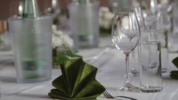 Une table dressée avec de la vaisselle transparente, une serviette verte et une bouteille d’eau.