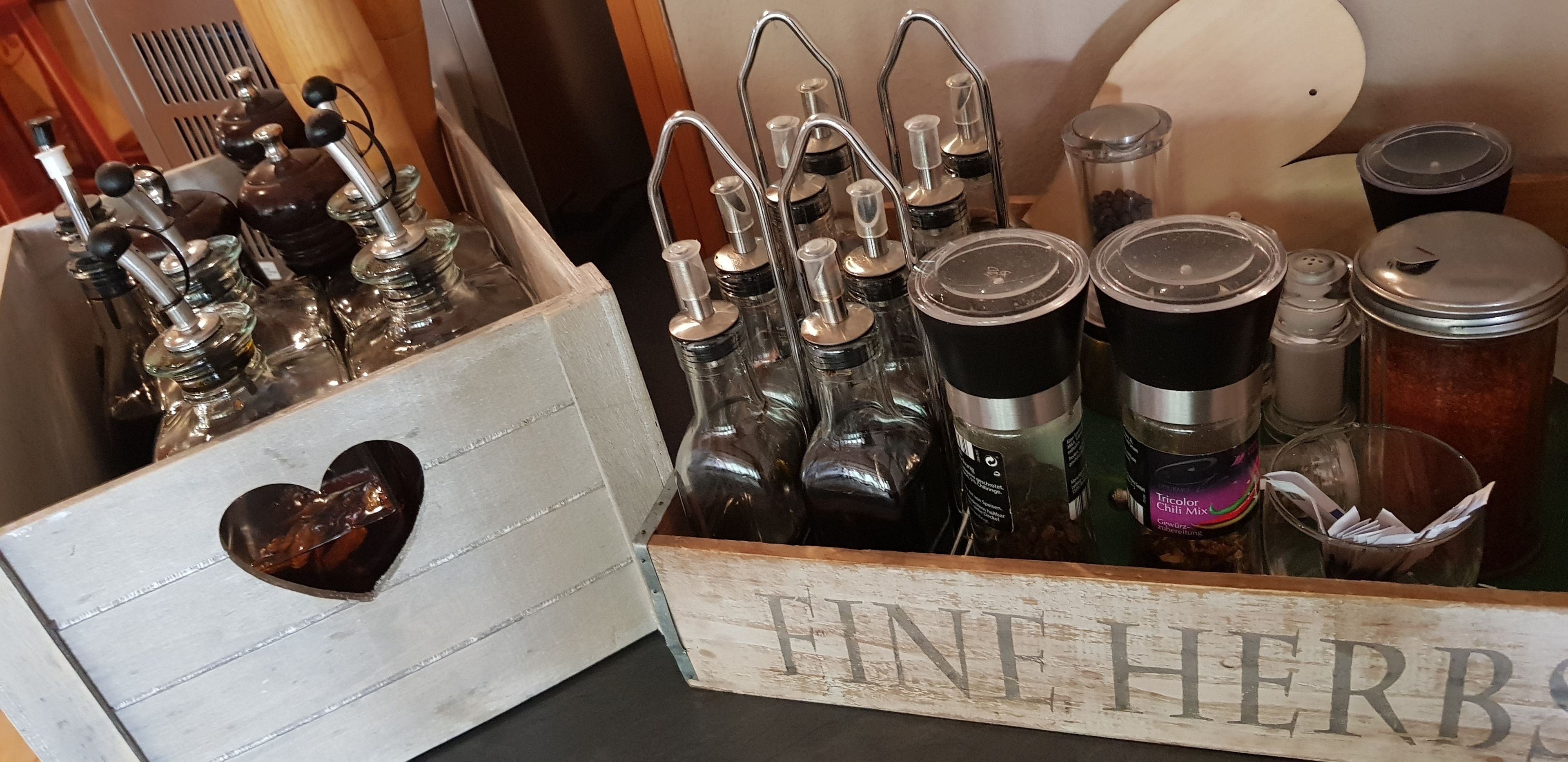Puisesta laatikosta, jonka kylkeen on kirjoitettu teksti ”FINE HERBS”, löytyy useita lasipulloja ja -astioita, joita on todennäköisesti käytetty nesteiden tai mausteiden säilytykseen.