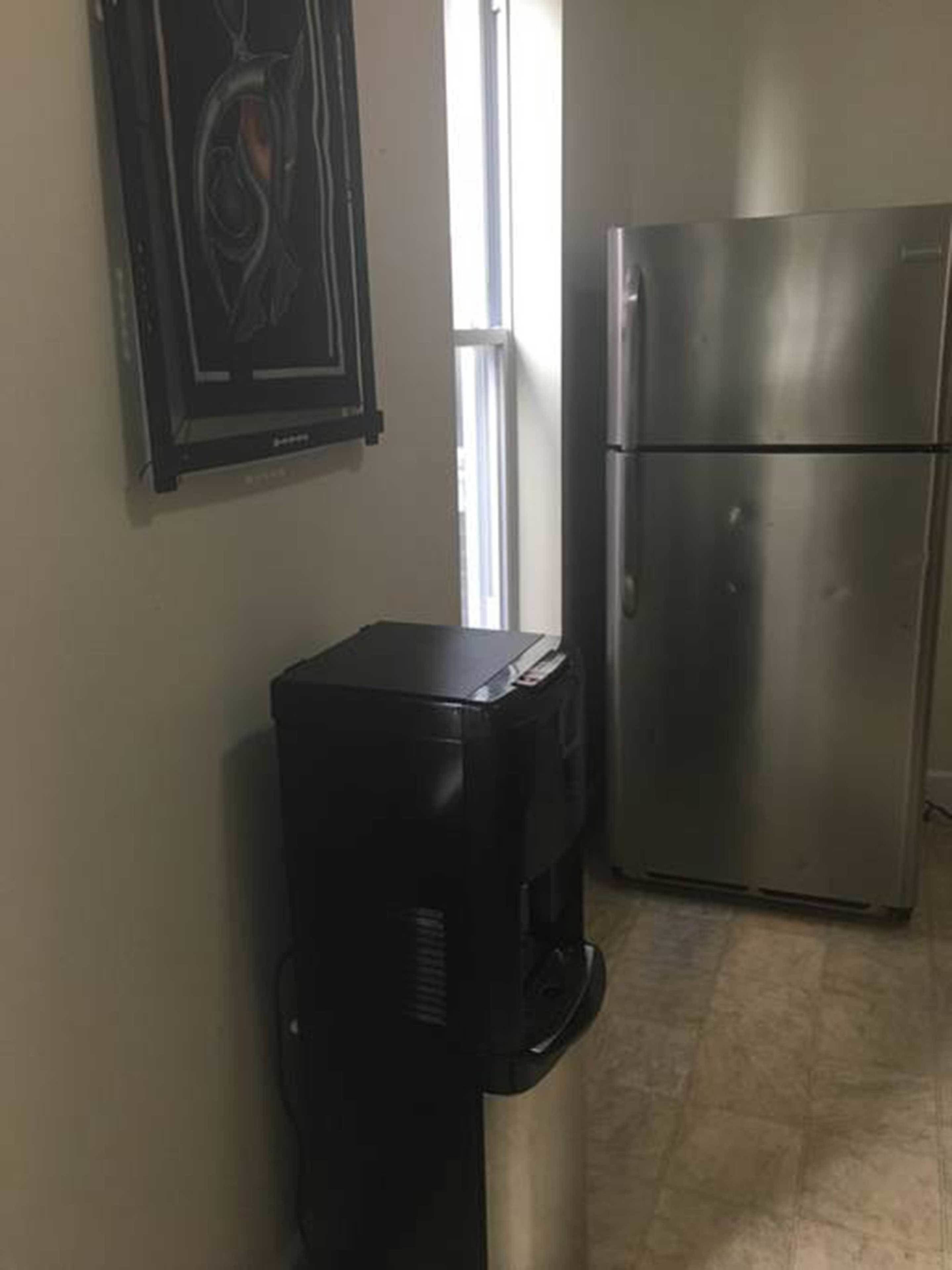 A kitchen with a coffee maker and a stainless steel refrigerator.