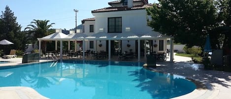 Una piscina al aire libre, sombrillas, sillones reclinables de piscina