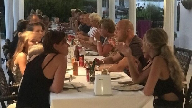 A group of people dining at an outdoor table with a white tablecloth, surrounded by chairs and a white umbrella. - Club Mel Holiday Resort (Ortaca)