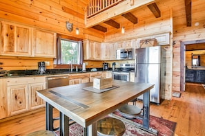 Cocina de cabaña de madera con una mesa de comedor, armarios, un microondas y un refrigerador.