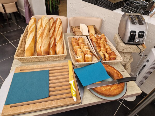 Una encimera de cocina con varios panes, un tostador y una tabla de cortar con un cuchillo.