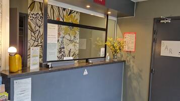 A hotel reception desk with a digital display, a reception sign, and a caution sign.