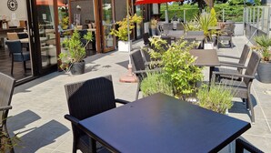 Un espace extérieur aménagé en terrasse, avec des tables et des chaises, de grands parasols et des plantes en pot.