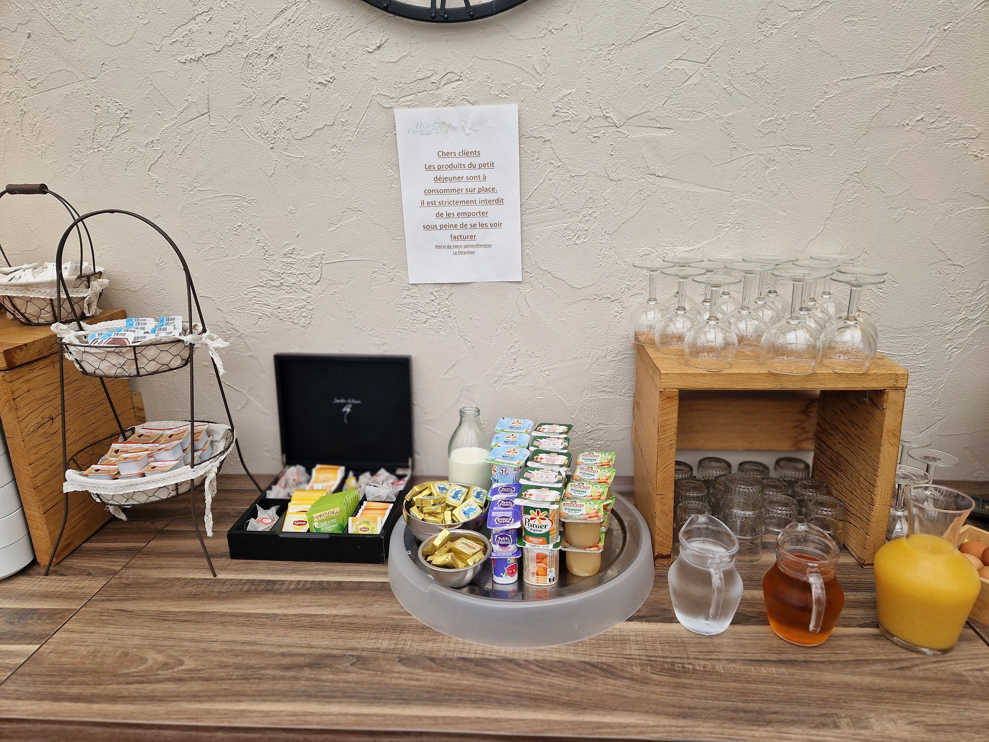 A buffet setup with various food items, a bottle of milk, and a selection of glasses and bottles.