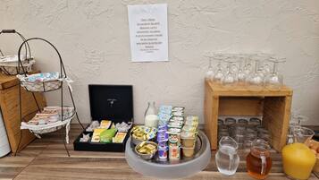 A buffet setup with various food items, a bottle of milk, and a selection of glasses and bottles.