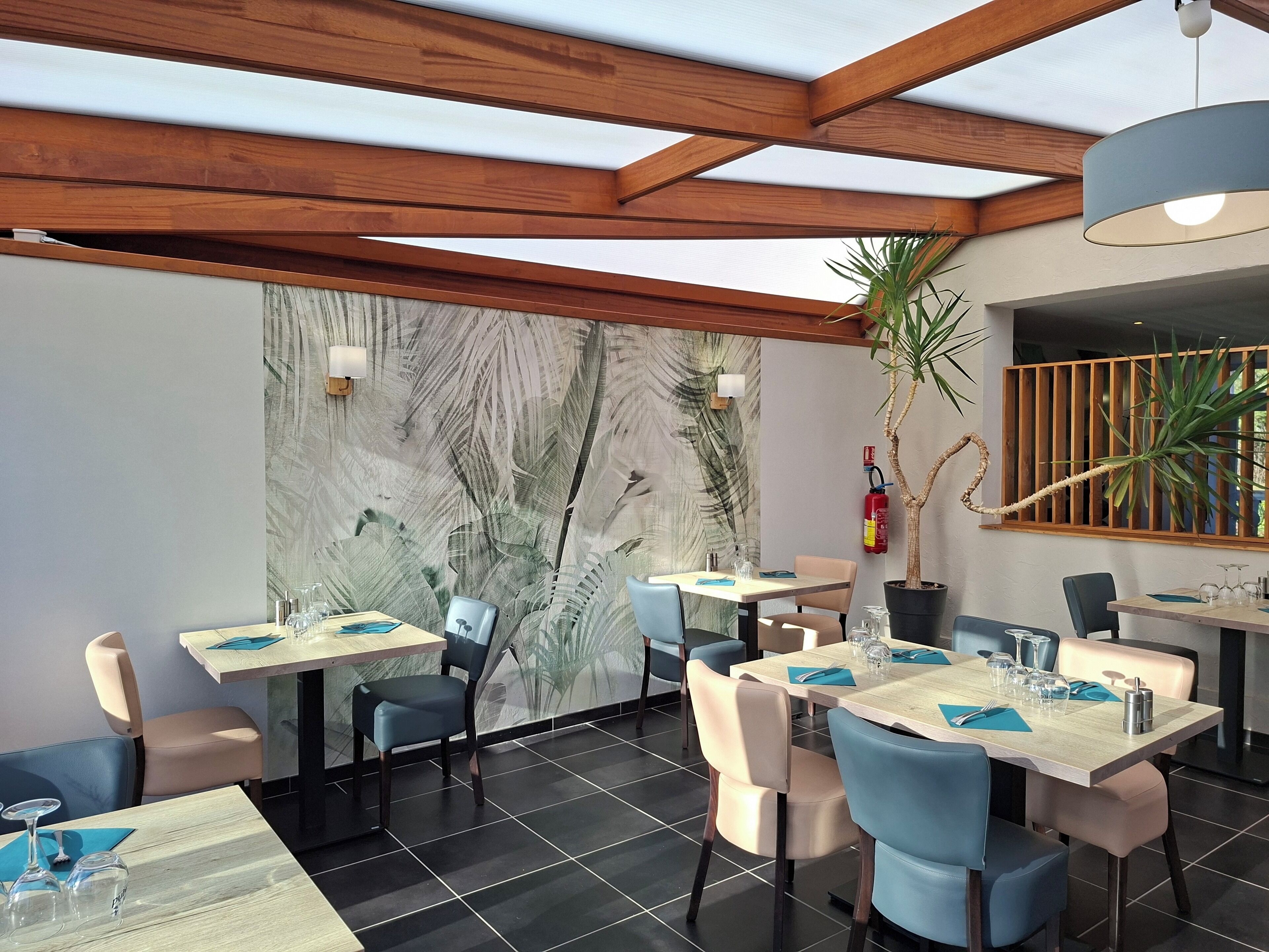 Un interno ristorante moderno con travi in legno, un grande murale e un estintore a parete.