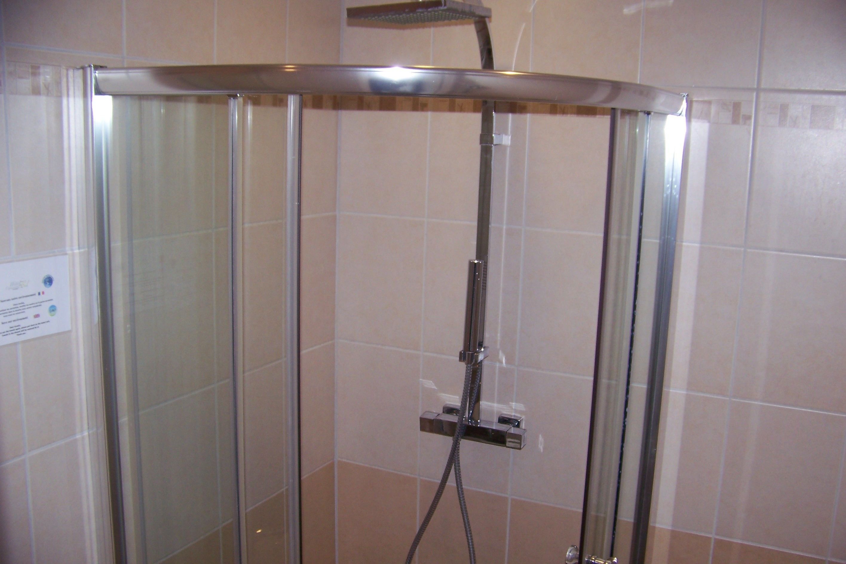 Una cabina de dutxa amb vidre i un braç de pluja.