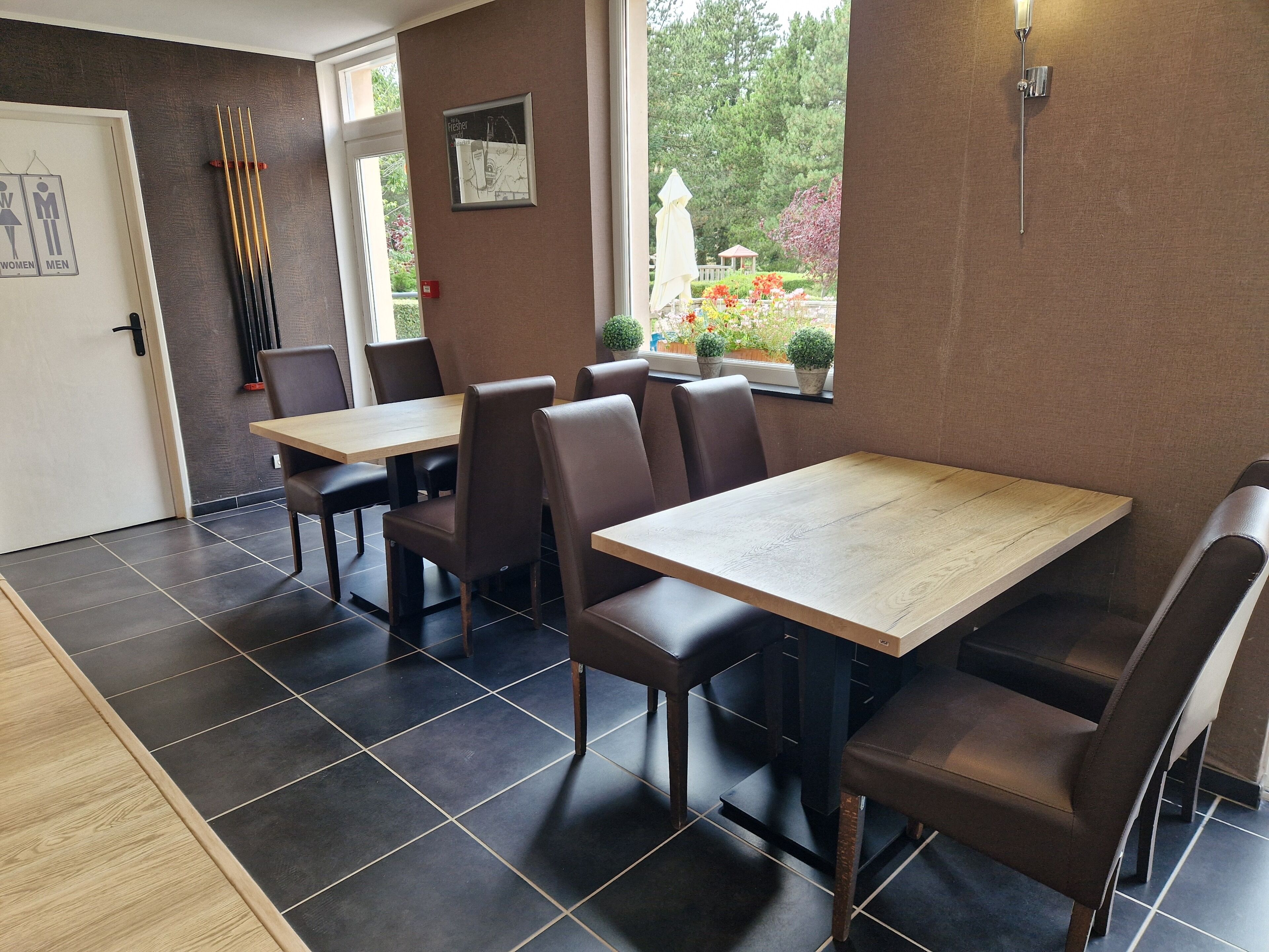 A restaurant interior with dark tiled floors, wooden tables, and brown upholstered booths.