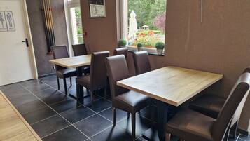 A restaurant interior with dark tiled floors, wooden tables, and brown upholstered booths.