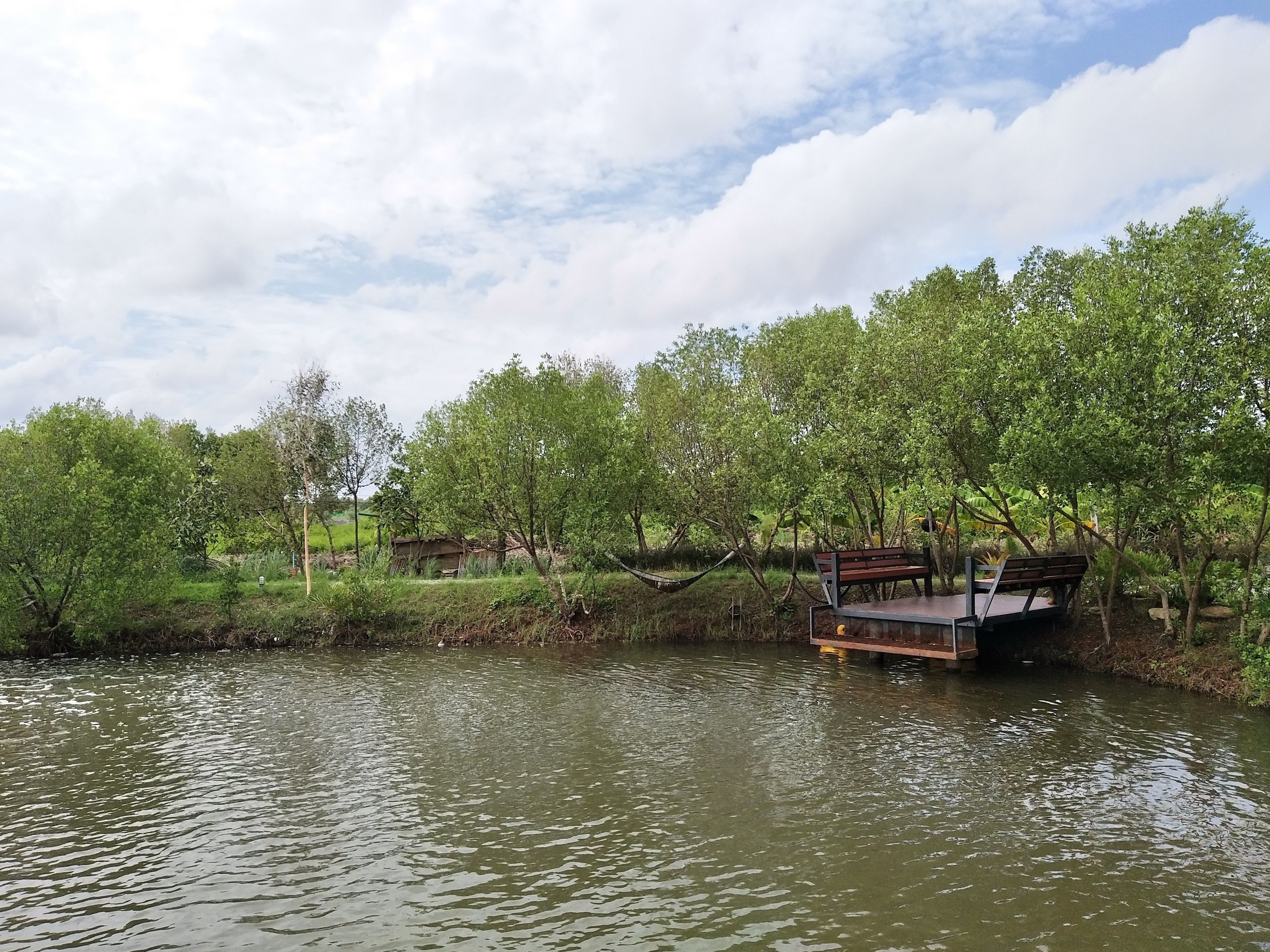 A riverside park with a wooden bench and a small wooden structure.
