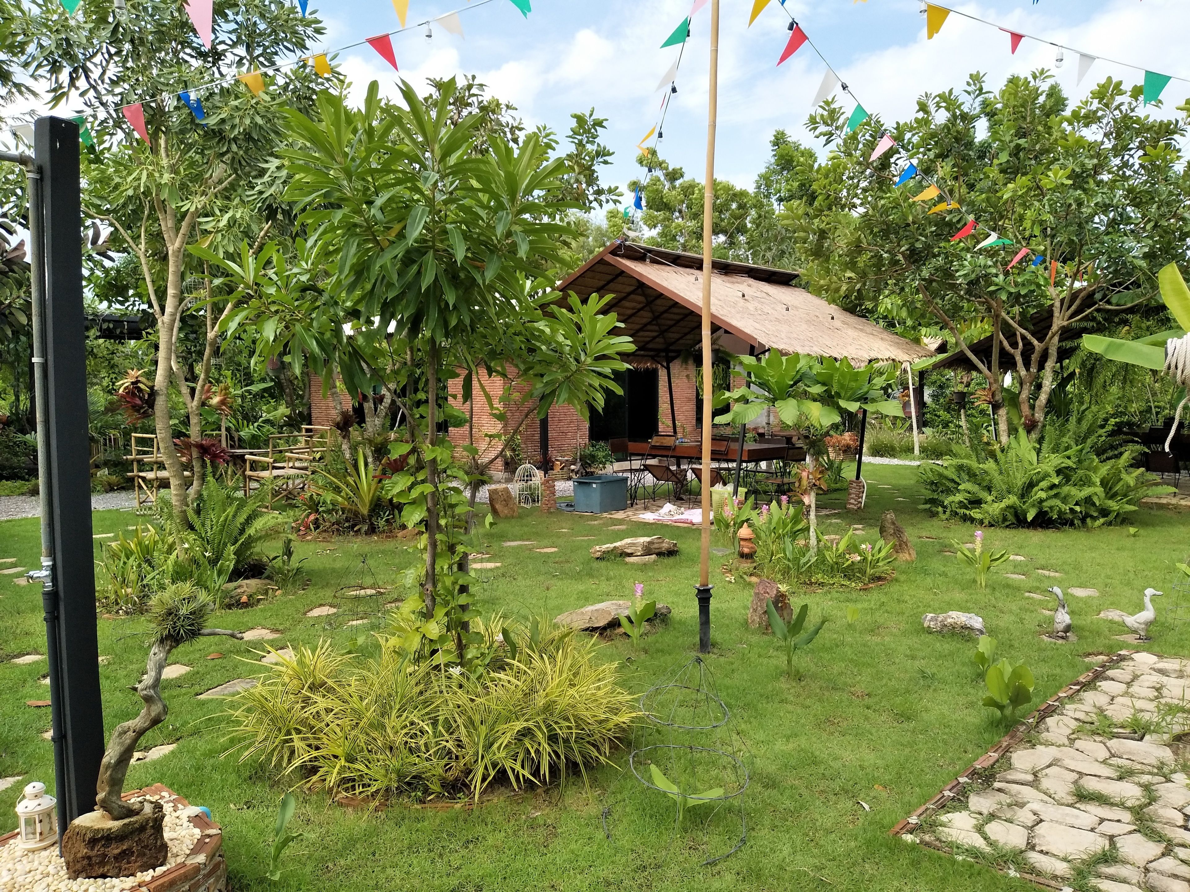 A rustic wooden cabin surrounded by lush greenery and a stone pathway.