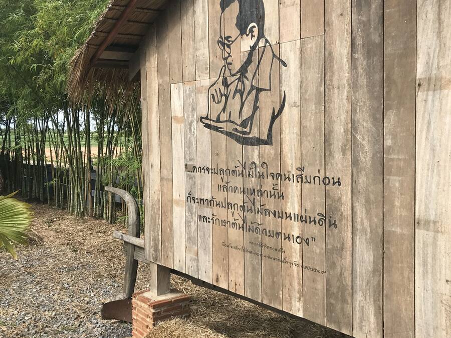 Une structure en bois ornée d’une fresque représentant une personne lisant un livre, ainsi que de texte en thaï.
