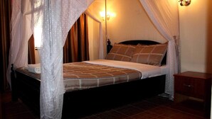 Un llit amb dosser, una taula de nit i una làmpada de paret.