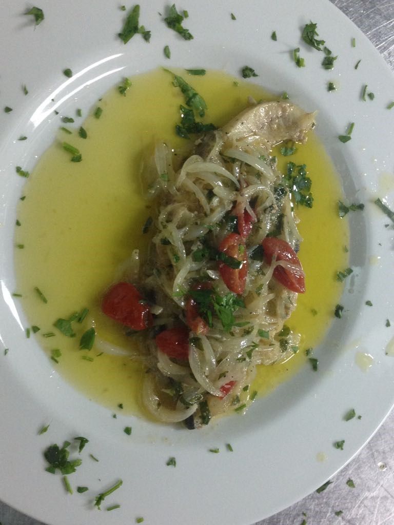 A plate of pasta with a yellow sauce, garnished with herbs and cherry tomatoes.