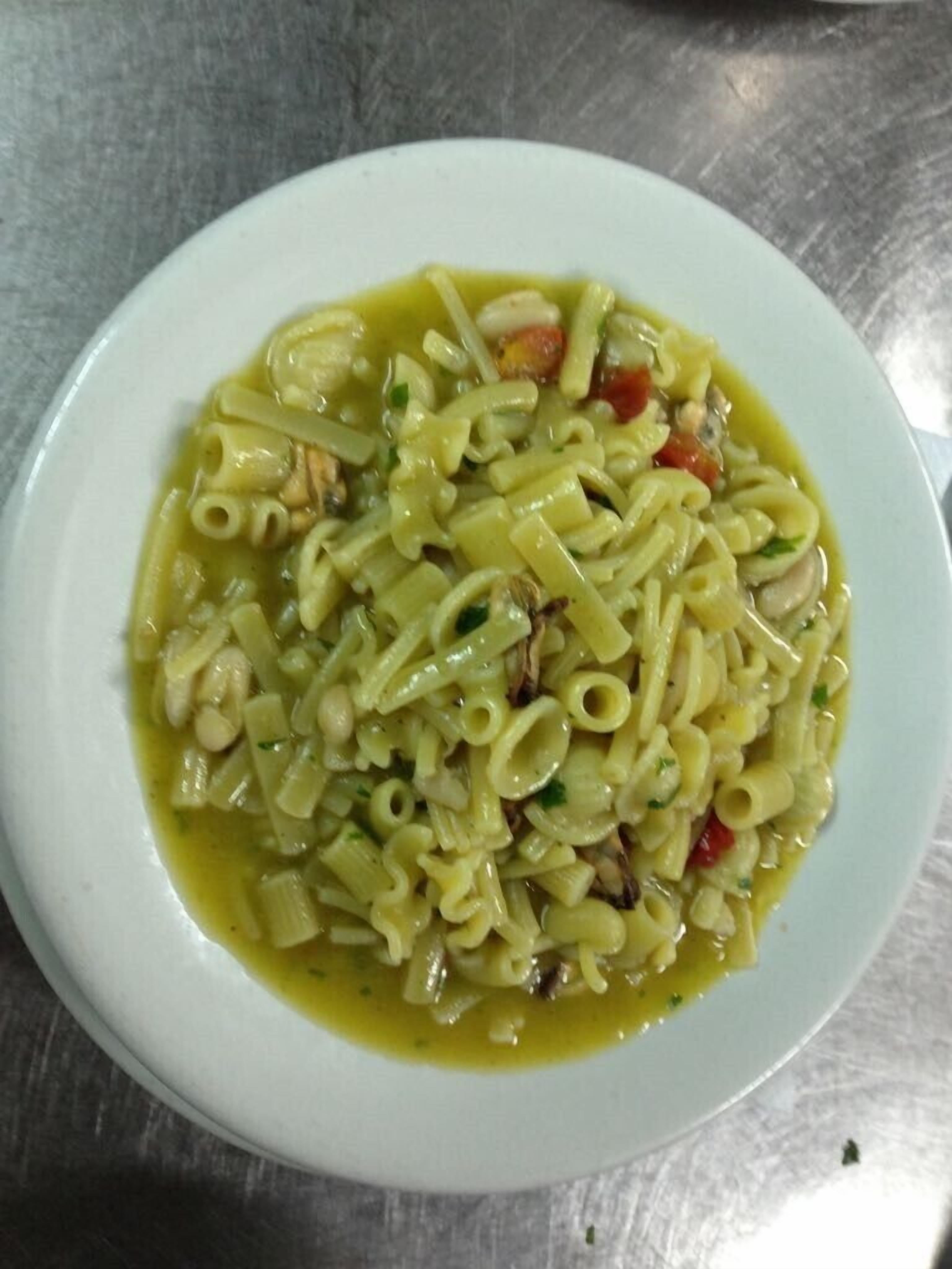A bowl of pasta with vegetables and a light sauce.