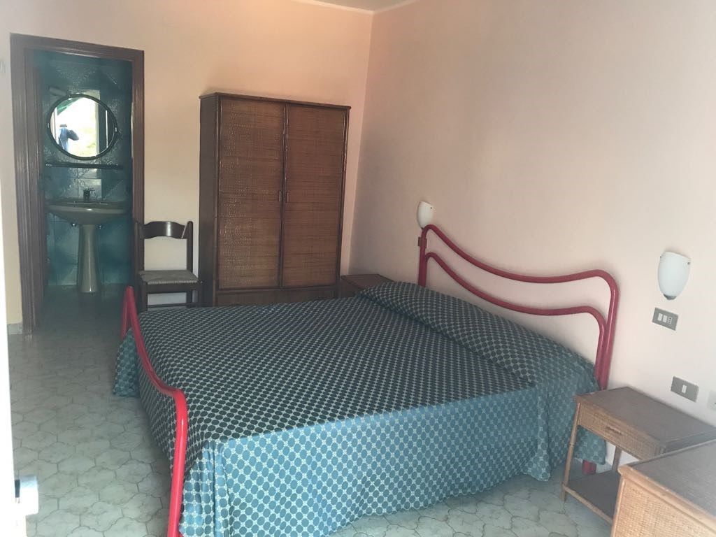 A room with a bed, a wardrobe, a small table, and a mirror.