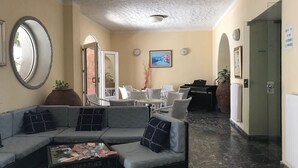 A lobby with a sofa, coffee table, and chairs. There are framed pictures on the wall and a potted plant. - Cinquestelle-albergo del centro storico (Centola)