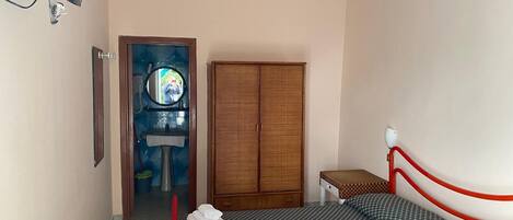 Un dormitorio con cama, armario, espejo y ventilador de techo.