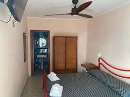 Un dormitorio con cama, armario, espejo y ventilador de techo.